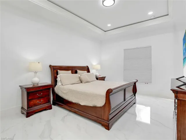 Bedroom with marble finish flooring, recessed lighting, and a tray ceiling
