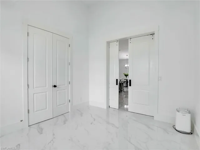 Unfurnished bedroom with marble finish floors and baseboards