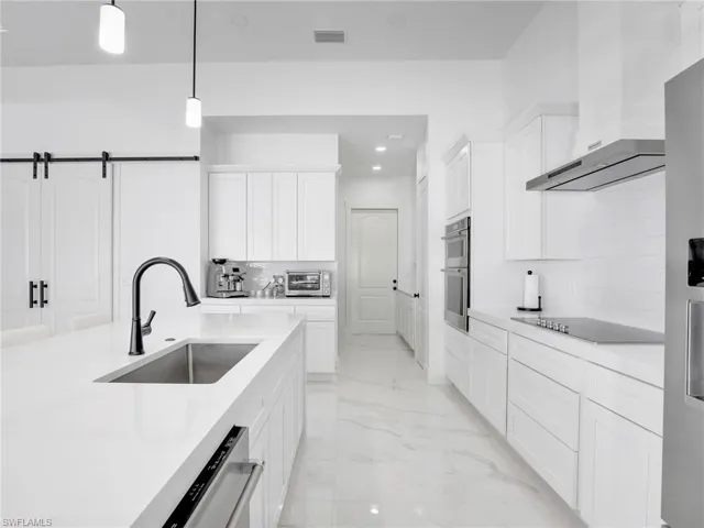 Kitchen featuring light marble finish flooring, white cabinets, recessed lighting, decorative backsplash, and decorative light fixtures