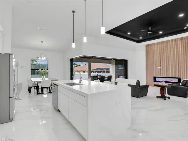 Kitchen with light marble finish flooring, open floor plan, freestanding refrigerator, white cabinetry, and light countertops