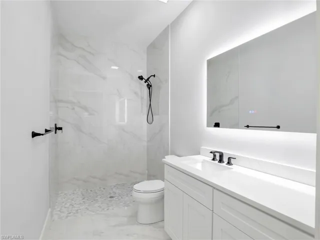 Full bath with vanity, a marble finish shower, and marble look tiles