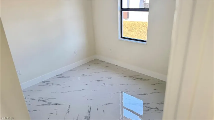 Spare room featuring marble finish floor and baseboards