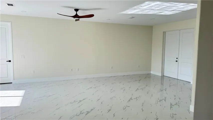 Unfurnished room featuring baseboards, marble finish floor, ceiling fan, and visible vents