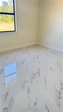 Spare room with marble finish floor and baseboards
