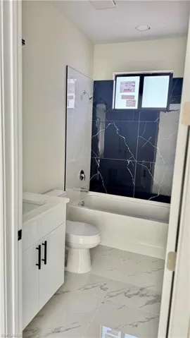 Bathroom with marble finish floor, toilet, shower / bath combination, and vanity
