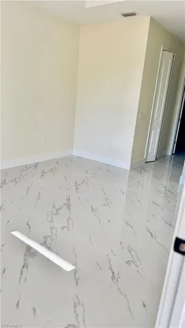 Unfurnished room with marble finish floor, baseboards, and visible vents