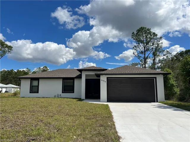 View of front facade with a front lawn, concrete driveway, an attached garage, and stucco siding