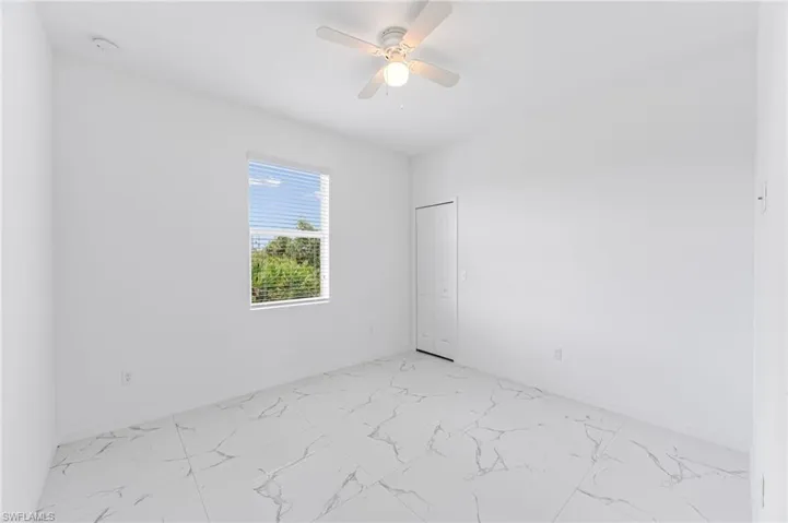 Empty room with a ceiling fan, marble finish floor, and baseboards