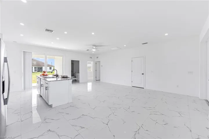 Kitchen with visible vents, open floor plan, white cabinetry, a sink, and an island with sink