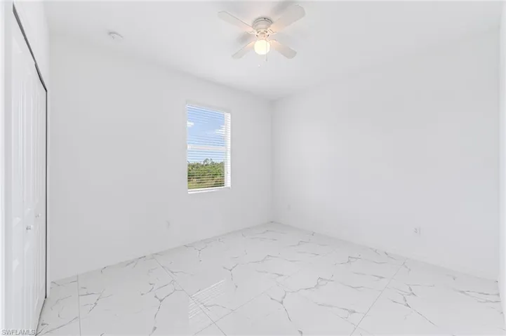 Unfurnished room with a ceiling fan, marble finish floor, and baseboards