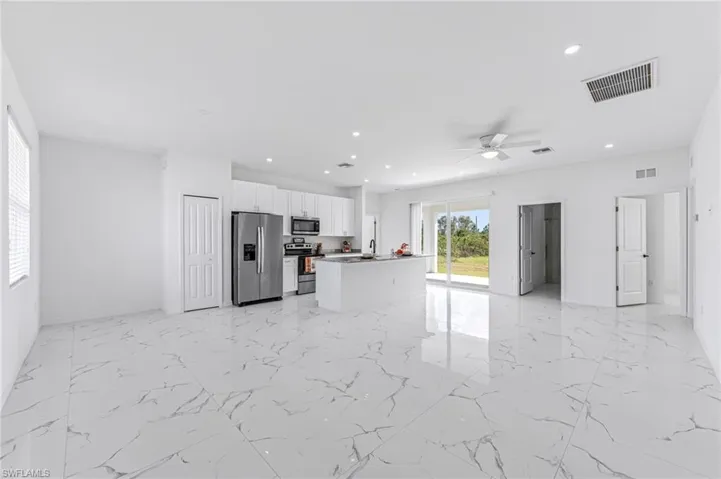 Kitchen with a sink, visible vents, white cabinetry, open floor plan, and appliances with stainless steel finishes