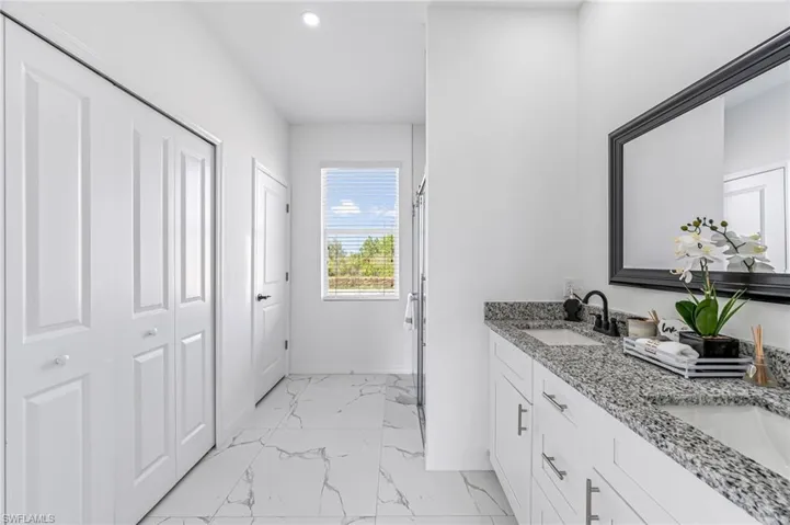 Bathroom with double vanity, a closet, baseboards, marble finish floor, and a sink