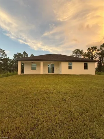 View of front facade with a front lawn, a patio area, and stucco siding