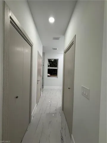 Hallway with baseboards and light marble finish flooring