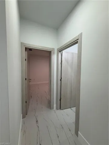 Hall with light marble finish flooring and baseboards