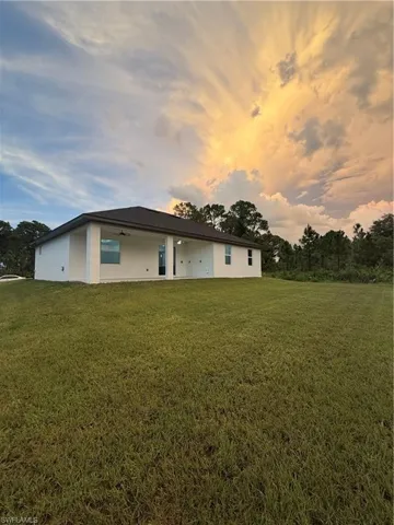 Back of property at dusk with a yard, a patio, and stucco siding