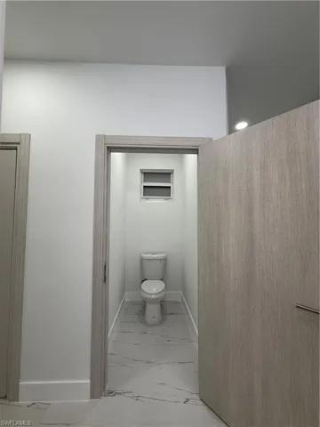 Bathroom featuring light marble finish flooring and toilet
