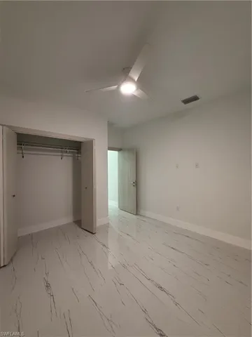 Unfurnished bedroom with a closet, ceiling fan, and light marble finish floors
