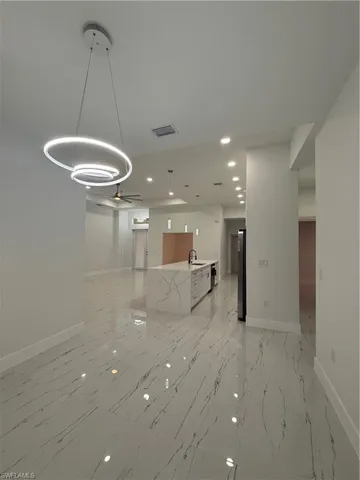 Kitchen featuring pendant lighting, recessed lighting, light stone counters, open floor plan, and a center island with sink