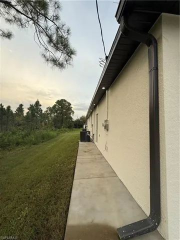 View of side of property with stucco siding, a lawn, and a patio