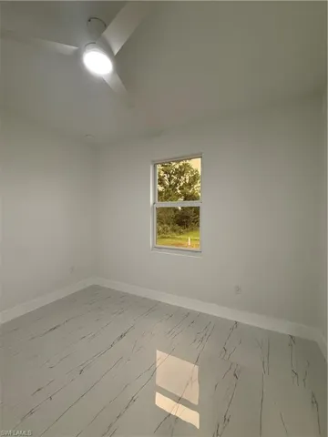 Spare room featuring light marble finish floors and a ceiling fan