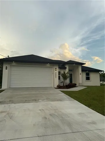 View of front of house featuring stucco siding, driveway, a garage, and a front lawn