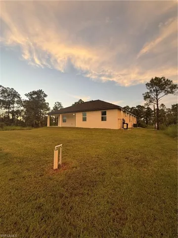 View of side of property featuring a yard, stucco siding, and a patio area