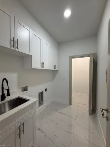 Laundry room featuring light marble finish flooring, cabinet space, hookup for a washing machine, and electric dryer hookup