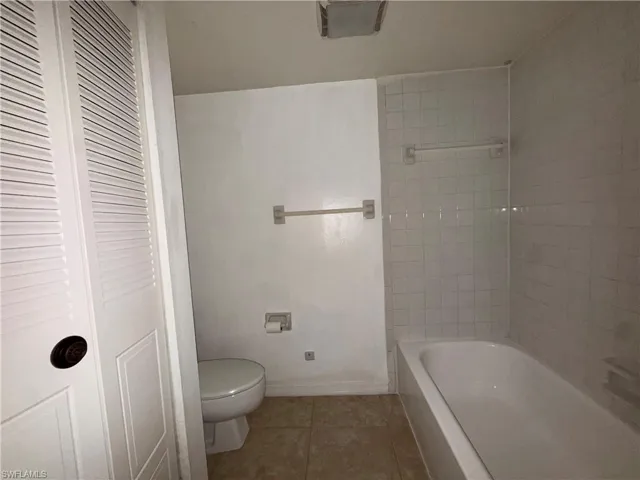 Bathroom featuring dark tile patterned floors and a closet