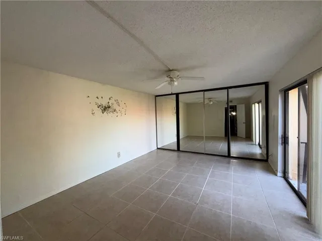 Unfurnished bedroom with a closet, a textured ceiling, tile patterned flooring, and a ceiling fan