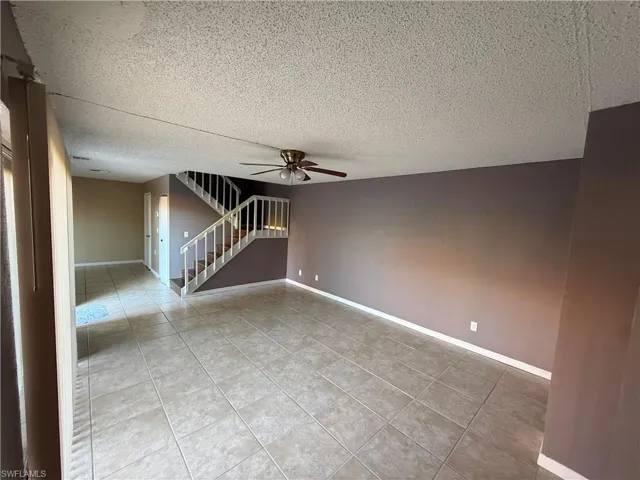 Spare room with ceiling fan, light tile patterned floors, and a textured ceiling