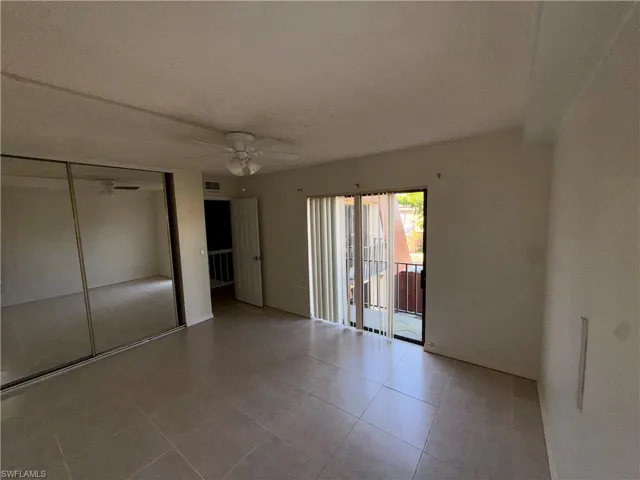 Unfurnished bedroom featuring a closet, access to outside, a ceiling fan, a textured ceiling, and light tile patterned floors