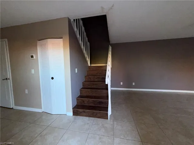 Staircase with tile patterned floors and baseboards