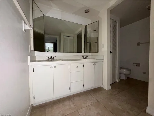 Bathroom with double vanity, a closet, and light tile patterned flooring