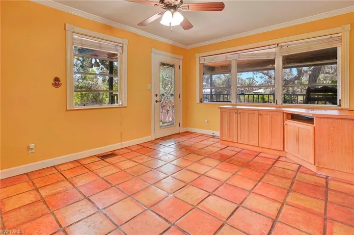 Tiled room with ceiling fan and crown molding