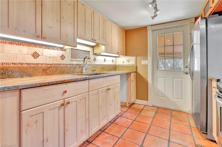 Kitchen featuring light brown cabinets, tasteful backsplash, track lighting, light tile floors, and sink