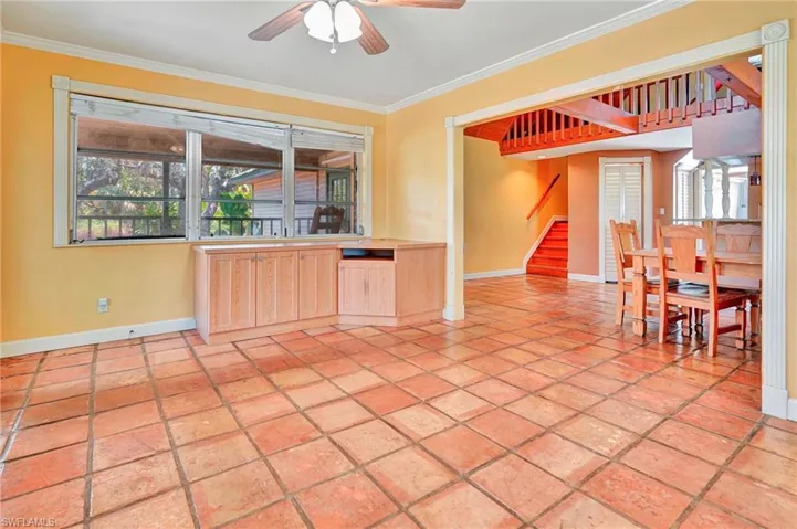 Unfurnished living room featuring ornamental molding, light tile flooring, and ceiling fan