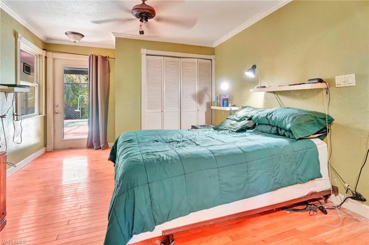 Bedroom featuring ceiling fan, a closet, hardwood / wood-style floors, access to outside, and ornamental molding
