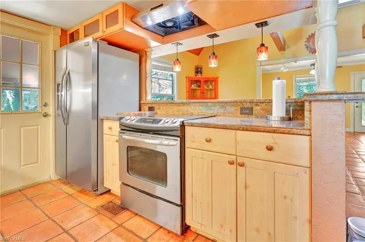 Kitchen with a healthy amount of sunlight, light tile flooring, pendant lighting, and appliances with stainless steel finishes