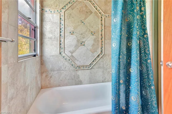 Bathroom with shower / bath combination with curtain