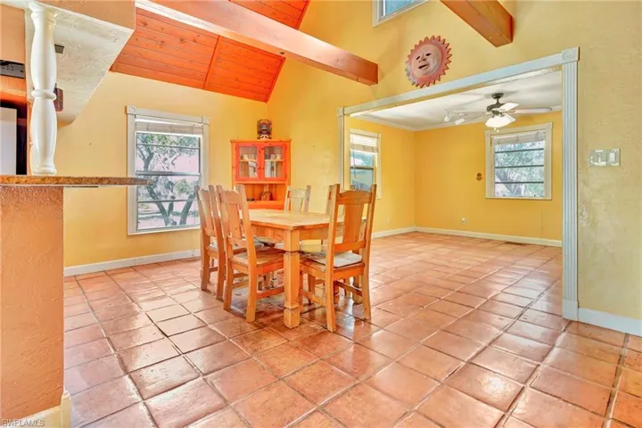 Tiled dining room with vaulted ceiling with beams, ceiling fan, and wood ceiling