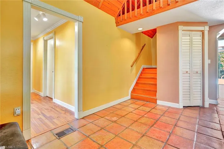 Foyer with tile flooring, ornamental molding, wood ceiling, and a textured ceiling