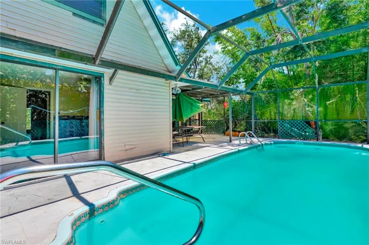 View of pool featuring a patio and glass enclosure