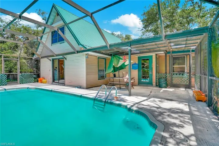 View of pool with a patio area and glass enclosure
