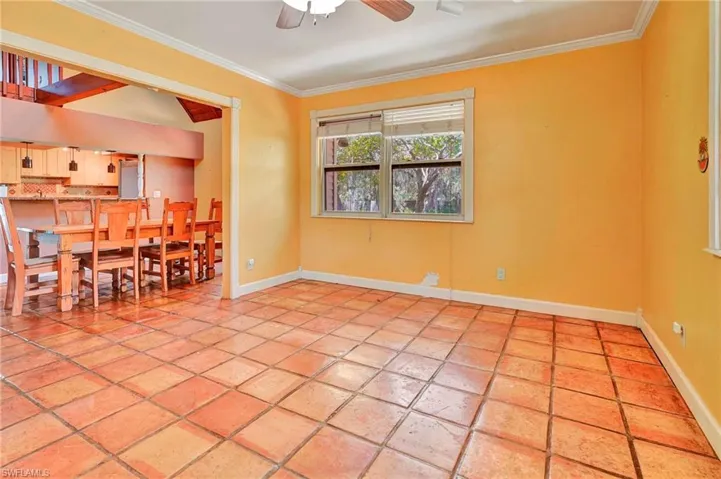 Empty room featuring ornamental molding, light tile flooring, and ceiling fan