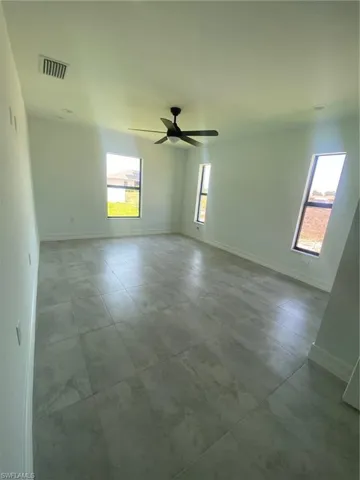 Tiled empty room featuring baseboards and a ceiling fan