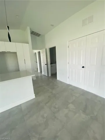 Unfurnished living room with vaulted ceiling and baseboards