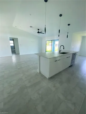 Kitchen featuring open floor plan, lofted ceiling, a sink, plenty of natural light, and a center island with sink