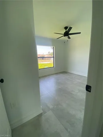 Tiled spare room featuring a ceiling fan and baseboards