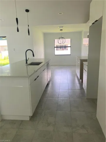 Kitchen featuring modern cabinets, a sink, white cabinetry, and recessed lighting